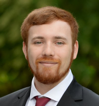 A young man wearing a suit and posing for a photo.