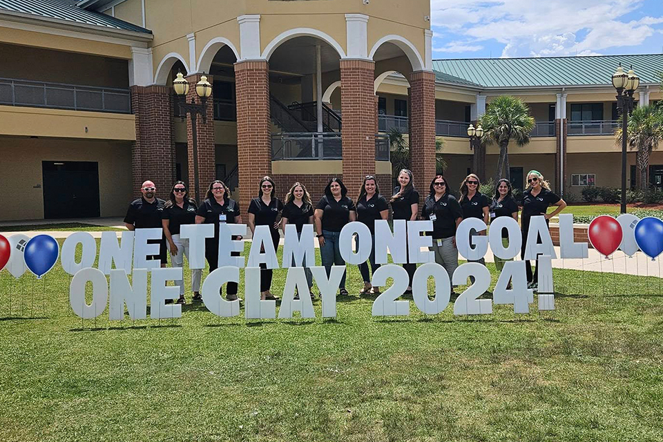 Doctors Inlet Teachers posing behind sign "One Team, One Goal"
