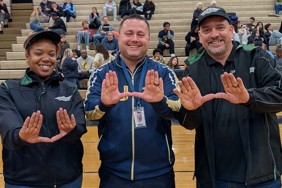 Thomas Ott and WingStop staff members throwing up a U with their hands