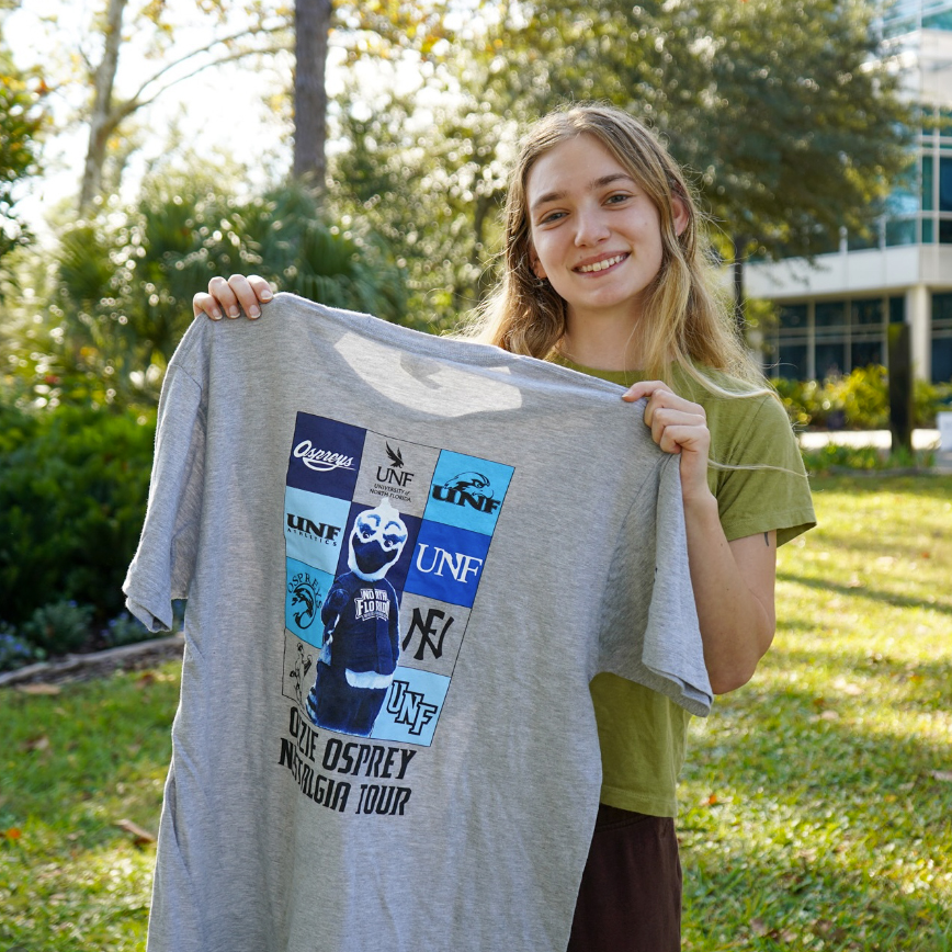 UNF student holding up Homecoming shirt