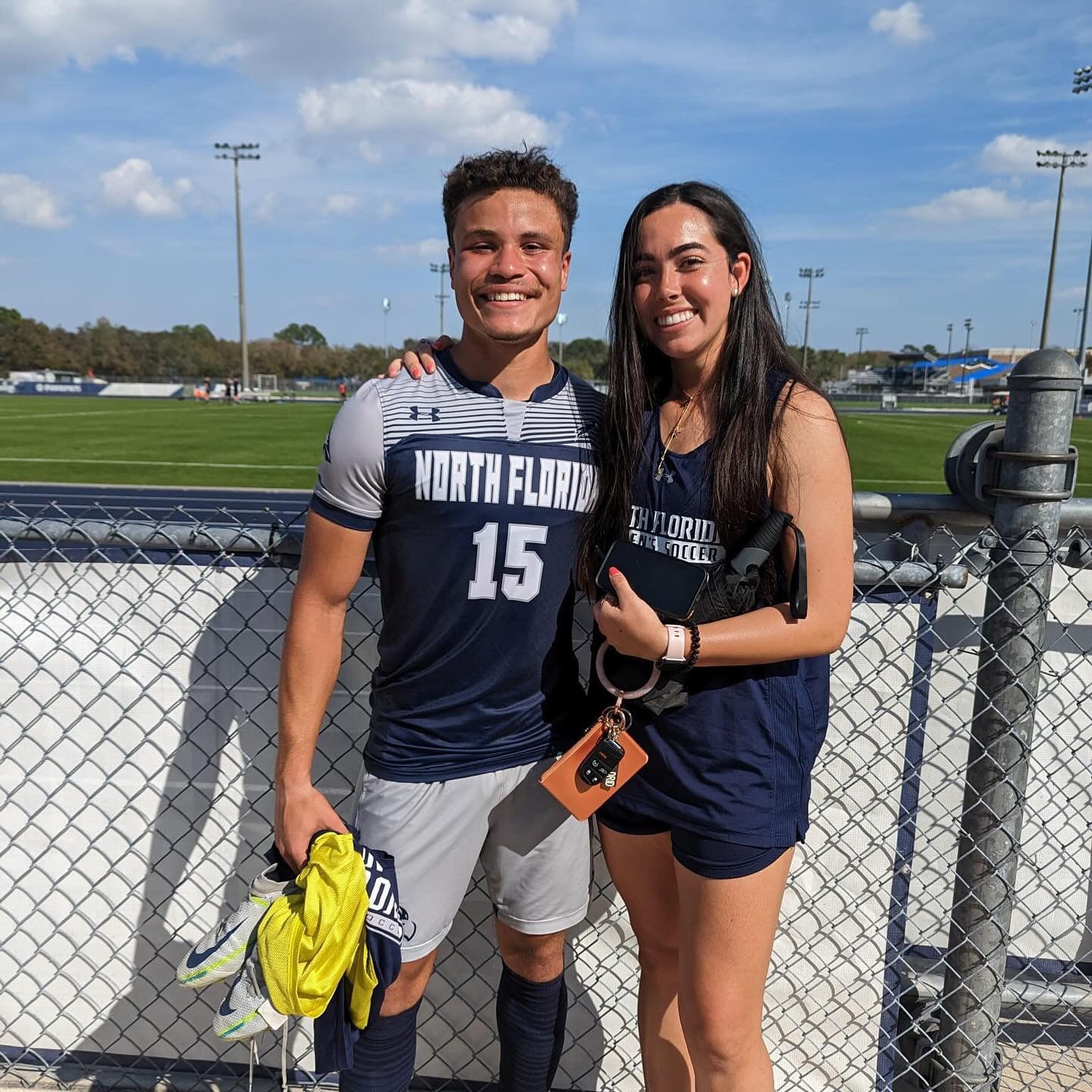 ariana and michael in their unf uniforms outside the field