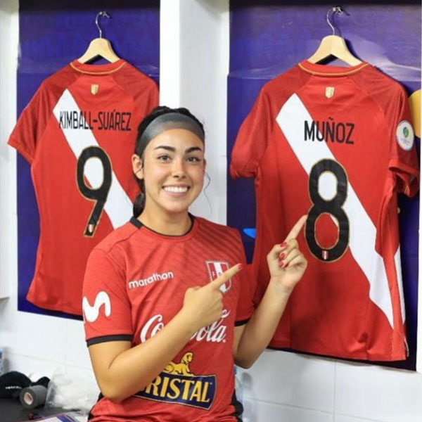 ariana pointing at her jersey in the locker room