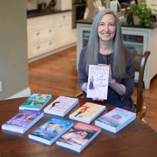 dianne holidng up a book at her kitchen table