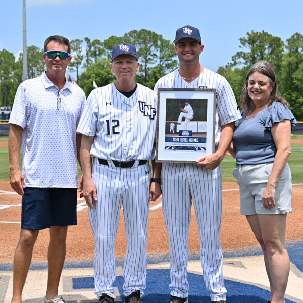 ohme holding his play picture with coach and parents