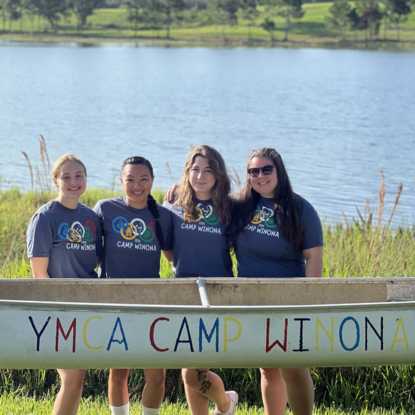 Sarah and her camp leaders behind a kayak