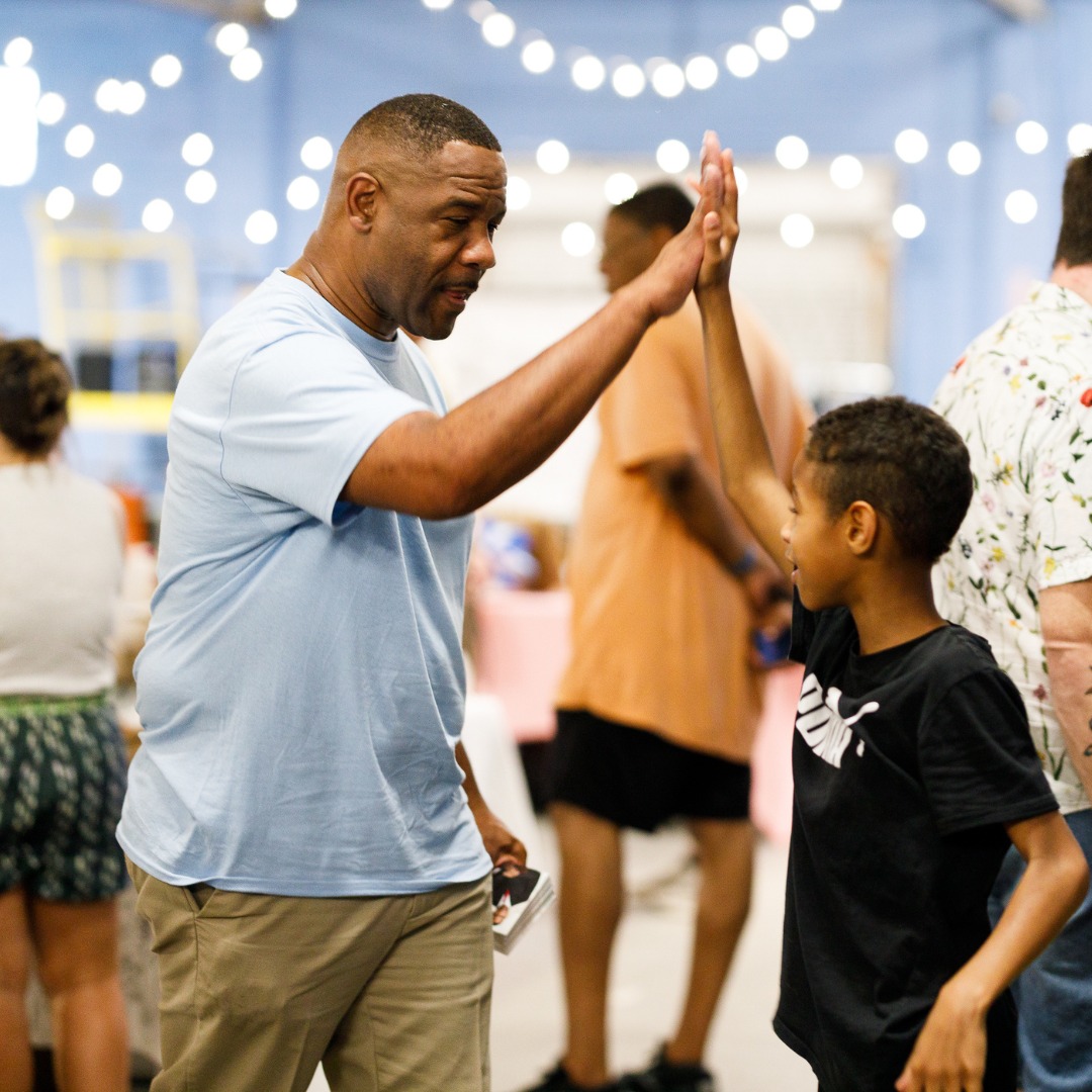 Hank Rogers high-fiving a child