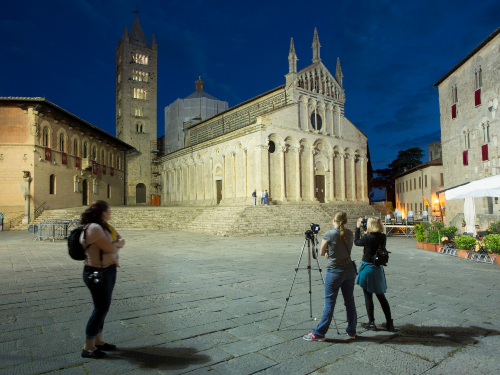 Two people taking a photo at night on a tripod of an old church