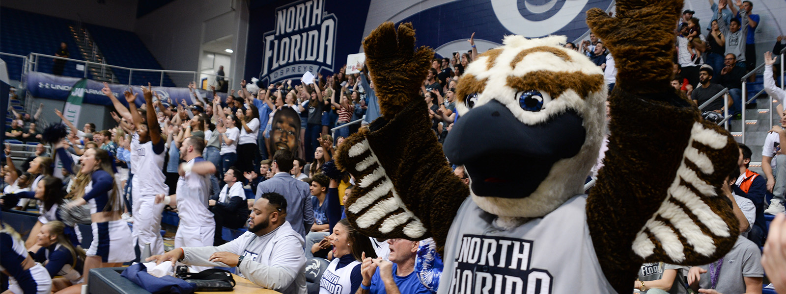Ozzie and fans at a UNF basketball game cheering together
