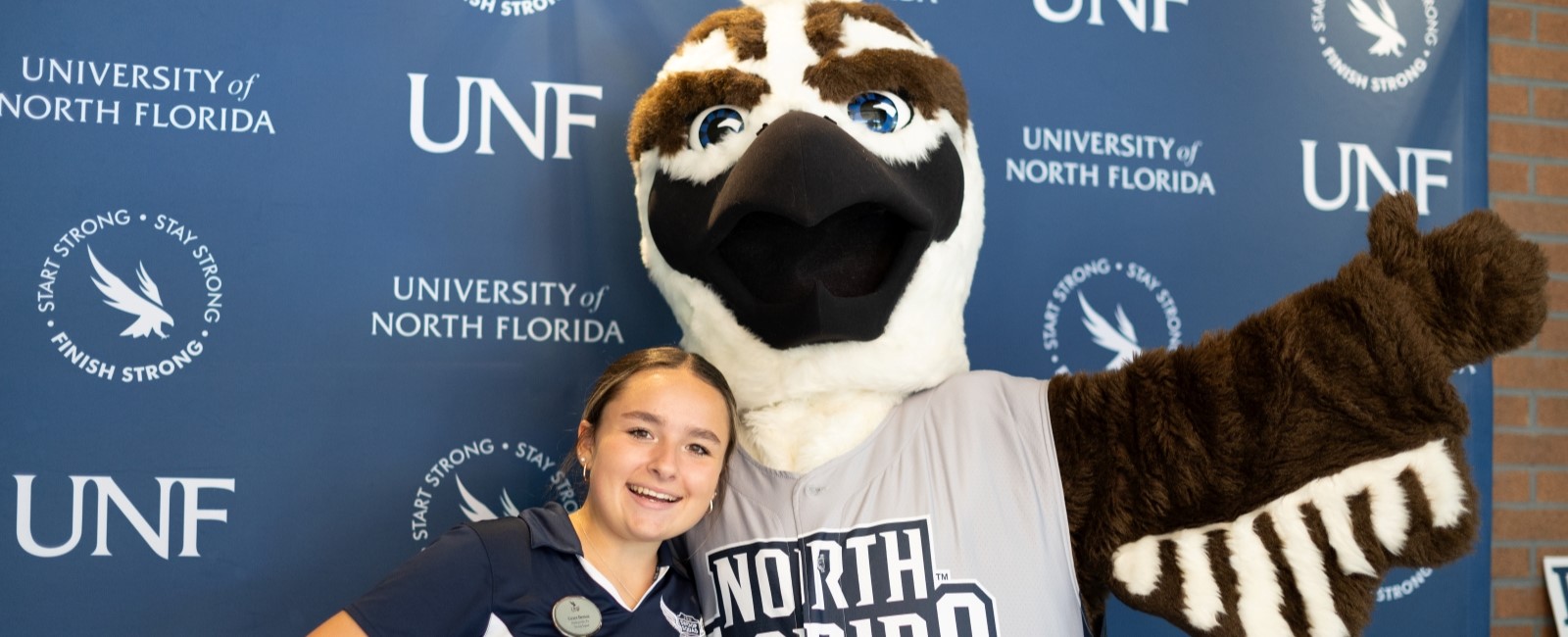 A UNF student tour guide and the UNF mascot posing for a photo.