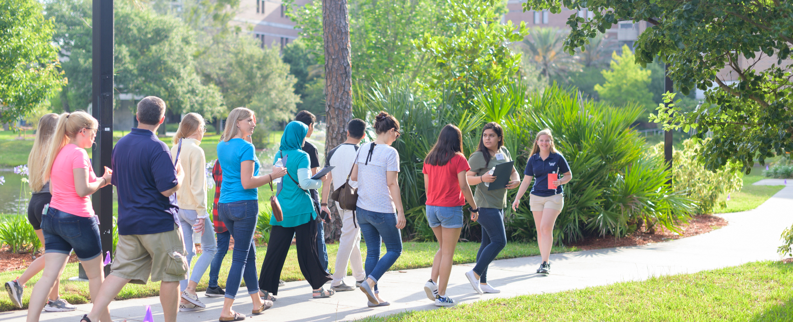 Tour group following a smiling female tour guide on UNF's campus by greenery