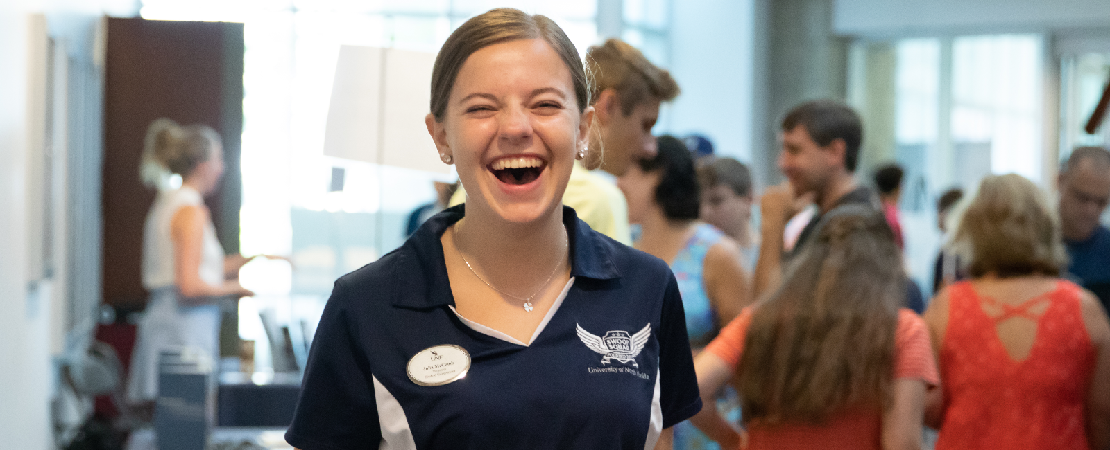 Female student in UNF Swoop Squad polo smiling big at the camera