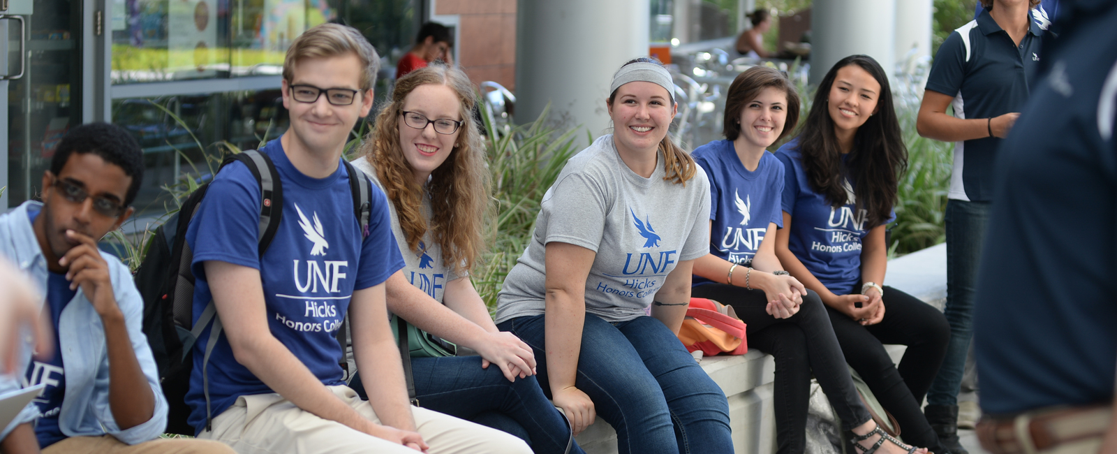 Group of students wearing Hicks Honors t-shirts and smiling looking away from the camera