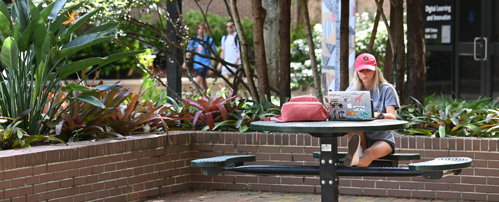 UNF female student sitting outside on campus at a picnic table with her laptop