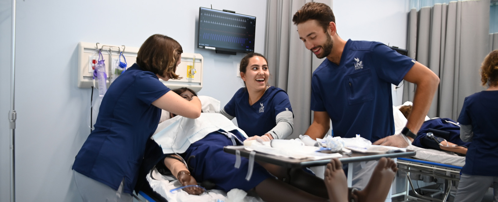 three nursing students working on a test dummy in hospital setting