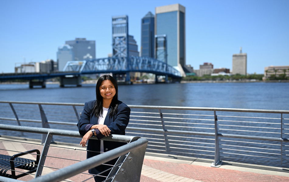 Student smiling while leaning on a railing in downtown Jacksonville