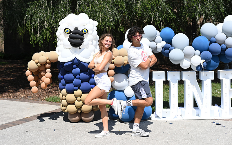 two students posing for a photo in front of a balloon osprey